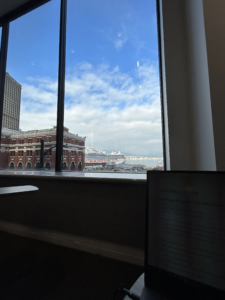 The view of Waterfront, the water, and North Vancouver taken from a chair inside of the Harbour Centre. A laptop is visible in the bottom right corner.